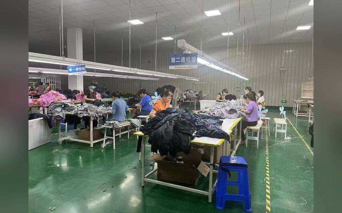 YucaiFJ quality-control station: a QC technician inspecting swimwear before packing — the stage you should never rush in a lead time